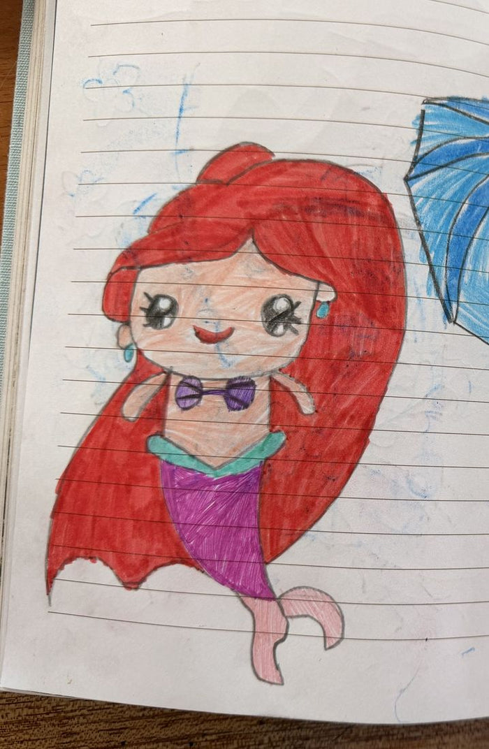 Colored pencil sketchbook drawing of a mermaid with long red hair